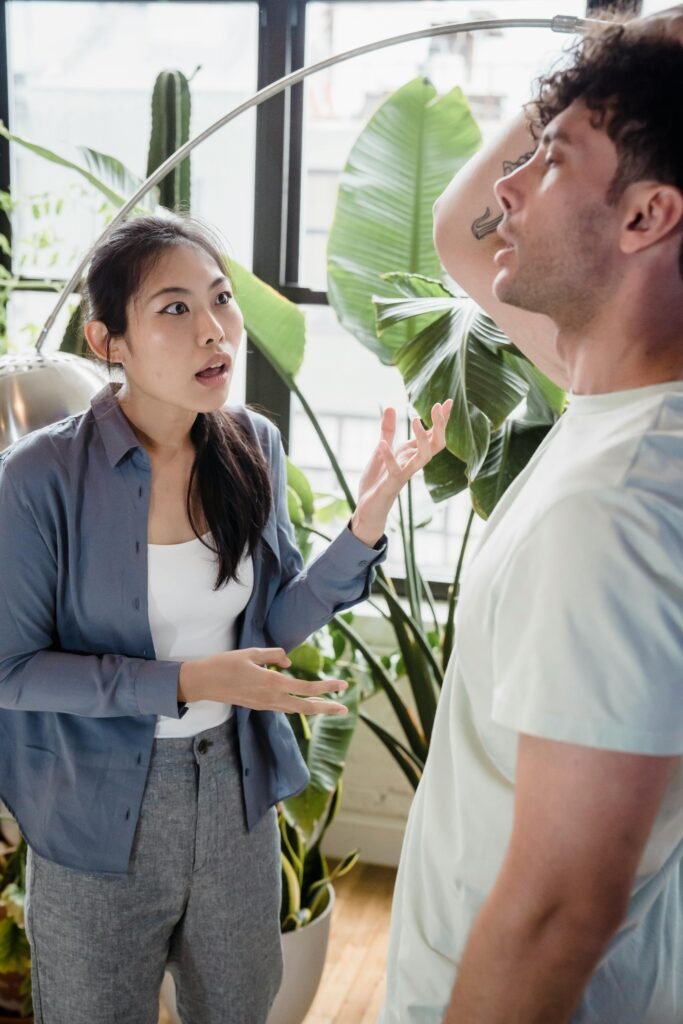 Asian woman and Caucasian man in a heated discussion, surrounded by indoor plants.